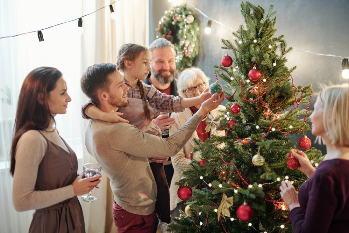 Les grands-parents, les parents et les enfants choisissent ensemble un sapin de Noël et le décorent pour la famille